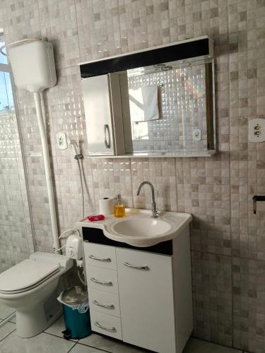 a bathroom with a toilet and a sink and a mirror at Pousada M&J in São Gabriel