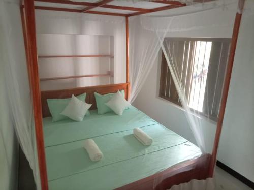 a bedroom with a bed with pillows and a window at White Shell in Tangalle