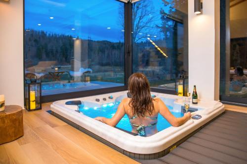 a woman sitting in a bath tub in a house at Valdora Forest Oasis - Spa Villa Fužine in Fužine