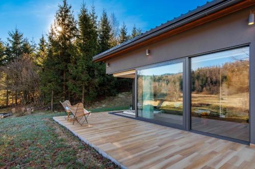 a wooden deck next to a house with large windows at Valdora Forest Oasis - Spa Villa Fužine in Fužine