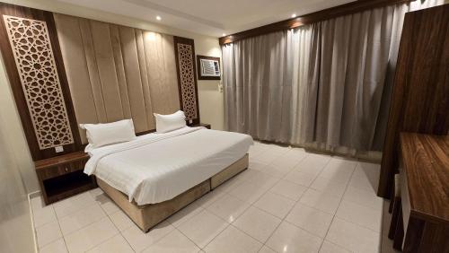 a bedroom with a bed with white sheets and pillows at ابراج التاج للشق المخدومة جدة in Jeddah