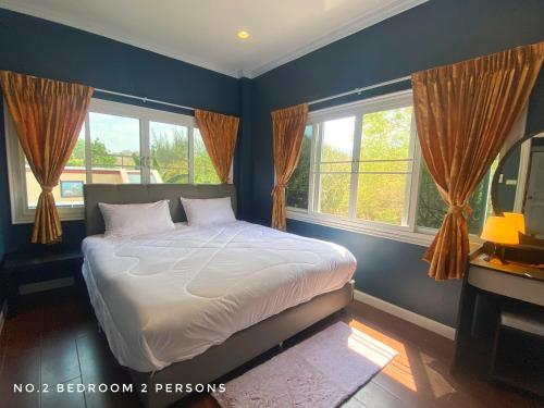 a bedroom with a bed with blue walls and windows at Mountain Pool Villa Suan Pheung in Suan Phung