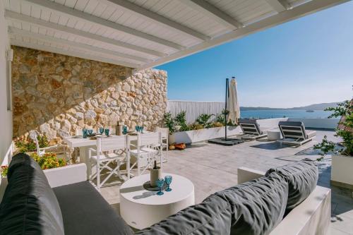 a patio with couches and tables and a stone wall at CASA ANNA BOUTIQUE LOFT Panoramic Sea View Apartment in Adamas