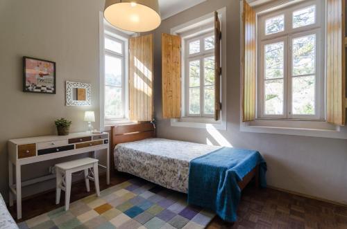 um quarto com uma cama, uma secretária e janelas em Chalet Monchique em Monchique