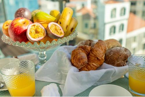 a table with a bowl of fruit and a plate of cookies at The Plaza Apartment in Funchal
