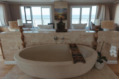 a large bath tub in a room with a bedroom at Dune Rose Yzerfontein Villa in Yzerfontein