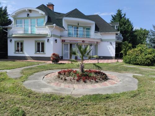 a large white house with a palm tree in a garden at Begónia Vendégház in Szigetszentmiklós