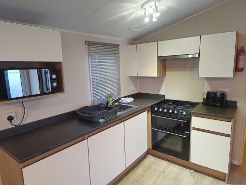 una cucina con armadi bianchi e un forno a piano cottura nero di Ollys House a Prestatyn