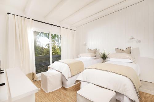 two beds in a white room with a window at Posada Arenas in José Ignacio