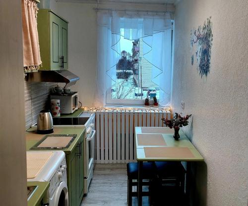 een keuken met een kleine tafel en een raam bij Ciemos pie Ingas Sedā 