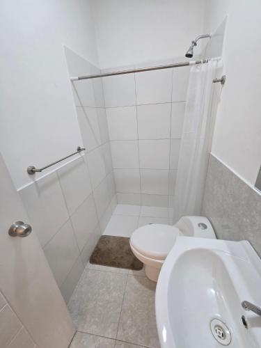 a white bathroom with a toilet and a sink at TRADEL Loreto in Iquitos