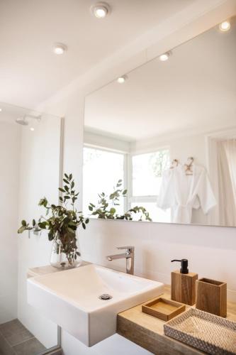 un bagno con un lavandino bianco e uno specchio di Posada Arenas a José Ignacio