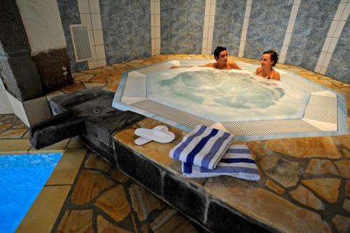 Due uomini in una jacuzzi in piscina di Hotel La Sapinière a Brioude