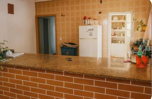 Il comprend une cuisine équipée d'un comptoir et d'un réfrigérateur blanc. dans l'établissement Casa Pé na Areia Centro de Mongaguá, à Mongaguá