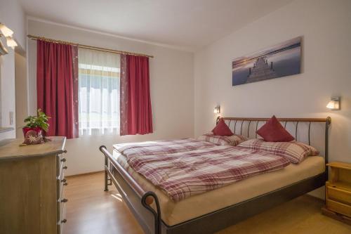 Schlafzimmer mit einem großen Bett und roten Vorhängen in der Unterkunft Appartement Vasilico in Söll