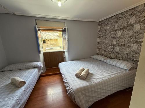 twee bedden in een kleine slaapkamer met een raam bij A Casiña de Coles in Gustey