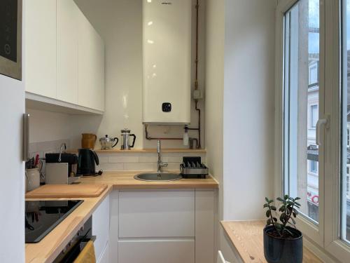 Una cocina con gabinetes blancos y un fregadero y una ventana. en Studio La cabine, en Wimereux