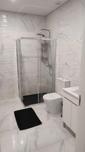 Un baño blanco con ducha y WC. en Casa da Praça, en Murtosa