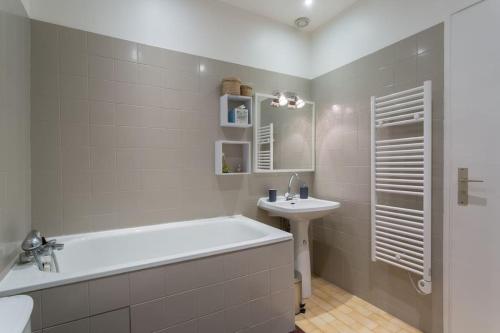 une salle de bain blanche avec une baignoire et un lavabo dans l'établissement Le 27 L, à Lyon