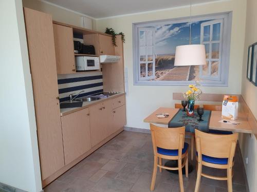 una cucina con tavolo, sedie e lavandino di Am Zingster Strand a Zingst