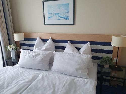 un letto bianco con cuscini bianchi sopra di Am Zingster Strand a Zingst