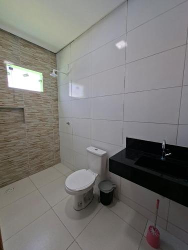 a white bathroom with a toilet and a sink at Casa completa de temporada- ReFÚGIO in Piranhas