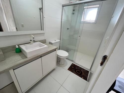 a white bathroom with a sink and a shower at Residencial Lazzari Apto 302 in Arroio do Sal