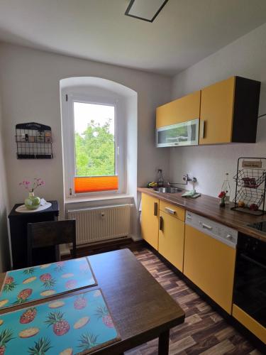 eine Küche mit gelben Schränken, einem Tisch und einem Fenster in der Unterkunft Altstadt-Domizil in Annaberg-Buchholz