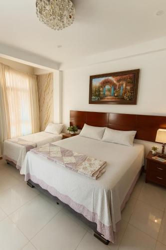 a bedroom with two beds and a chandelier at Casa Deluxe Hotel Talara in Talara