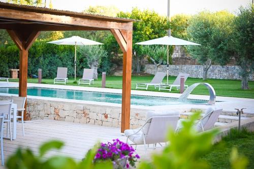 una piscina con sedie e ombrelloni bianchi di Villa Ostuni a Monopoli
