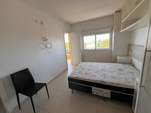 a bedroom with a bed and a chair in it at Residencial Lazzari Apto 302 in Arroio do Sal