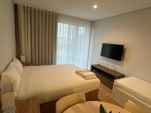 a hotel room with a bed and a flat screen tv at New Douro Tower 203 With Parking in Vila Nova de Gaia