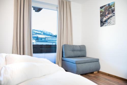 a bedroom with a chair and a bed and a window at Dili Appartement in Altenmarkt im Pongau