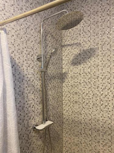 a shower with a shower head in a bathroom at EdenRose Guest House in Kwabenya