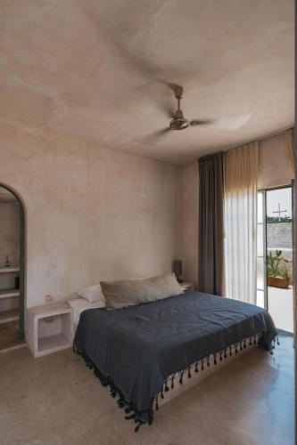 a bedroom with a bed with a ceiling fan at Villa Petit Comité in Mérida