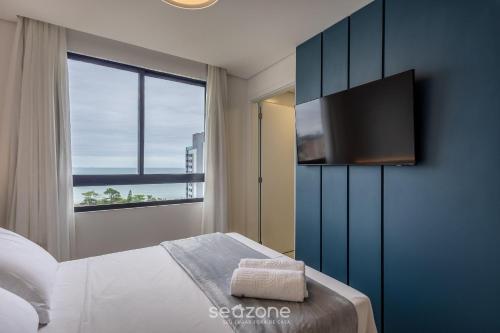 a bedroom with a bed and a flat screen tv at Estadia completa com piscina e academia a 400m da Praia da Armação - SKL in Penha