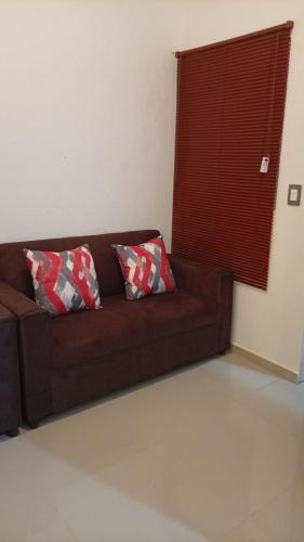 een bruine bank met 2 kussens in de woonkamer bij Joseline House in San Miguel