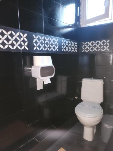 a bathroom with a white toilet and a black wall at jim villa in Andravída