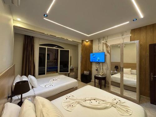 Una habitación de hotel con dos camas y un televisor de pantalla plana. en Nisut Pyramids Hotel, en El Cairo