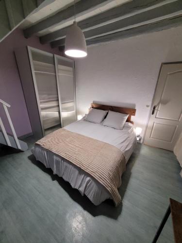 een slaapkamer met een groot bed met witte kussens bij Echappée verte et jacuzzi proche de Paris in Vert-le-Grand