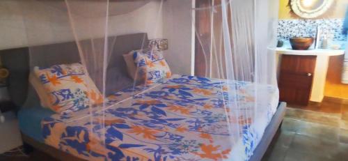 ein Schlafzimmer mit einem Bett mit einer blauen und orangefarbenen Bettdecke in der Unterkunft OROKA EDEN in Ambondrona