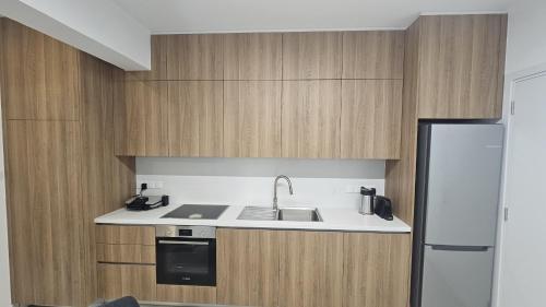 a kitchen with wooden cabinets and a sink and a refrigerator at STAY Engomi Gem 2 in İncirli