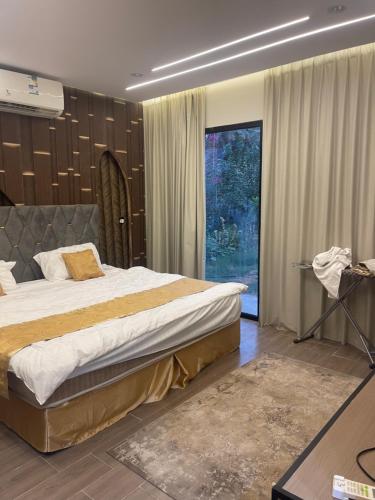 Un dormitorio con una cama grande y una ventana grande. en شاليه نخله, en Al Ula