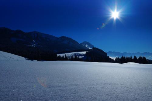 a snow covered field with the sun in the sky at Ferienwohnung am Bichl - Stilvoll mit Terrasse, Carport und Gästekarte in Lechbruck