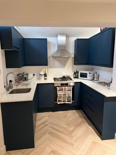 a kitchen with blue cabinets and white counter tops at Victorian Cottage in Central Richmond in Richmond upon Thames