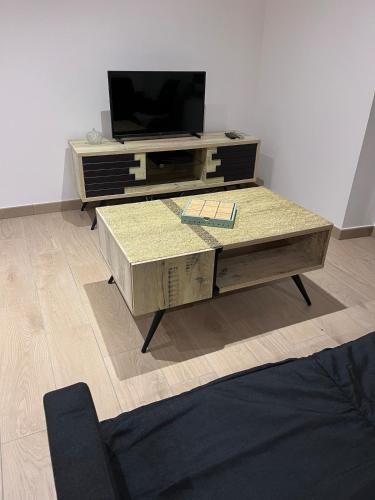 Una sala de estar con televisión y una mesa de café. en La p'tite maison, en Courgains