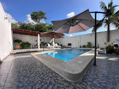 a swimming pool with an umbrella next to a building at Casa de playa Iberico in Caleta Grau