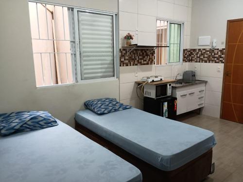 Una pequeña habitación con dos camas y una cocina. en Parque Ecológico Studios, en Indaiatuba