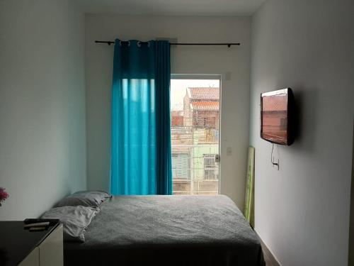 1 dormitorio con 1 cama con cortina azul y ventana en Parque Ecológico Studios, en Indaiatuba