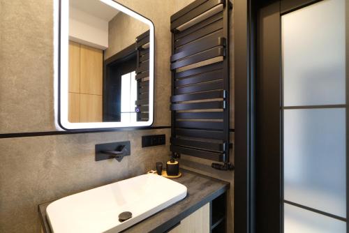 a bathroom with a sink and a mirror at Apartament Loft Olszynki Park in Rzeszów
